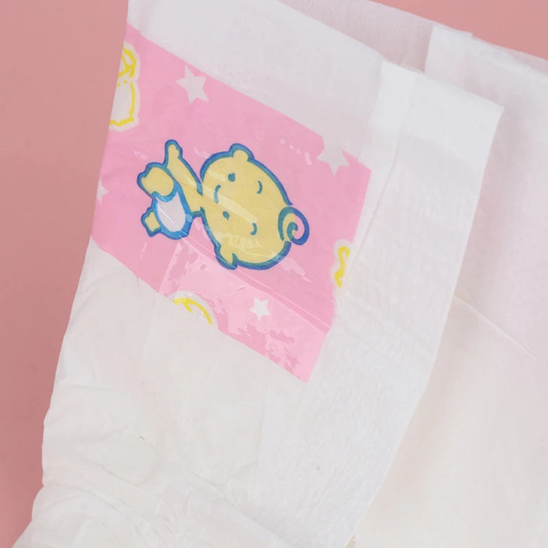 Close-up da banda rosa da fralda Reborn com desenho de elefante amarelo sobre fundo rosa, fundo geral rosa.