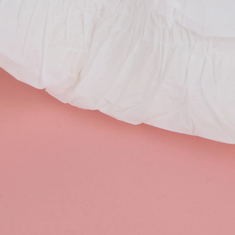 Detalhe do elástico e cintura da fralda Reborn branca sobre fundo rosa.